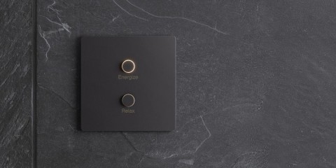 Matte black, Lutron Alisse keypad mounted on a black marble wall. Two buttons that read energize and relax.  