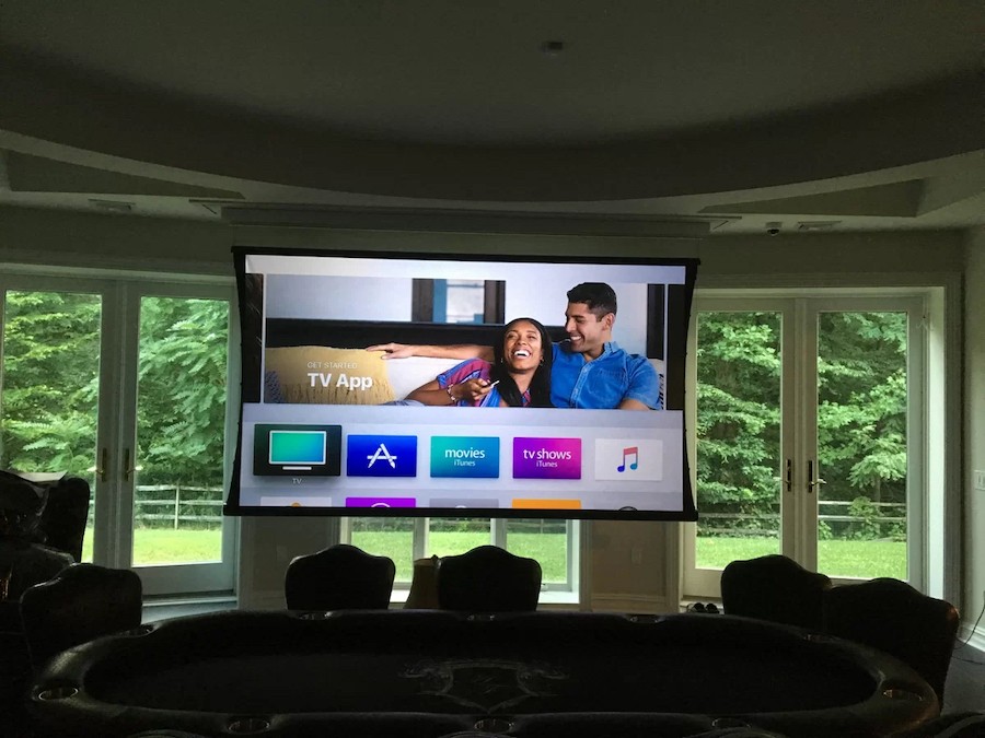  motorized TV lift lowers a projection screen in front of floor-to-ceiling windows in a living room 